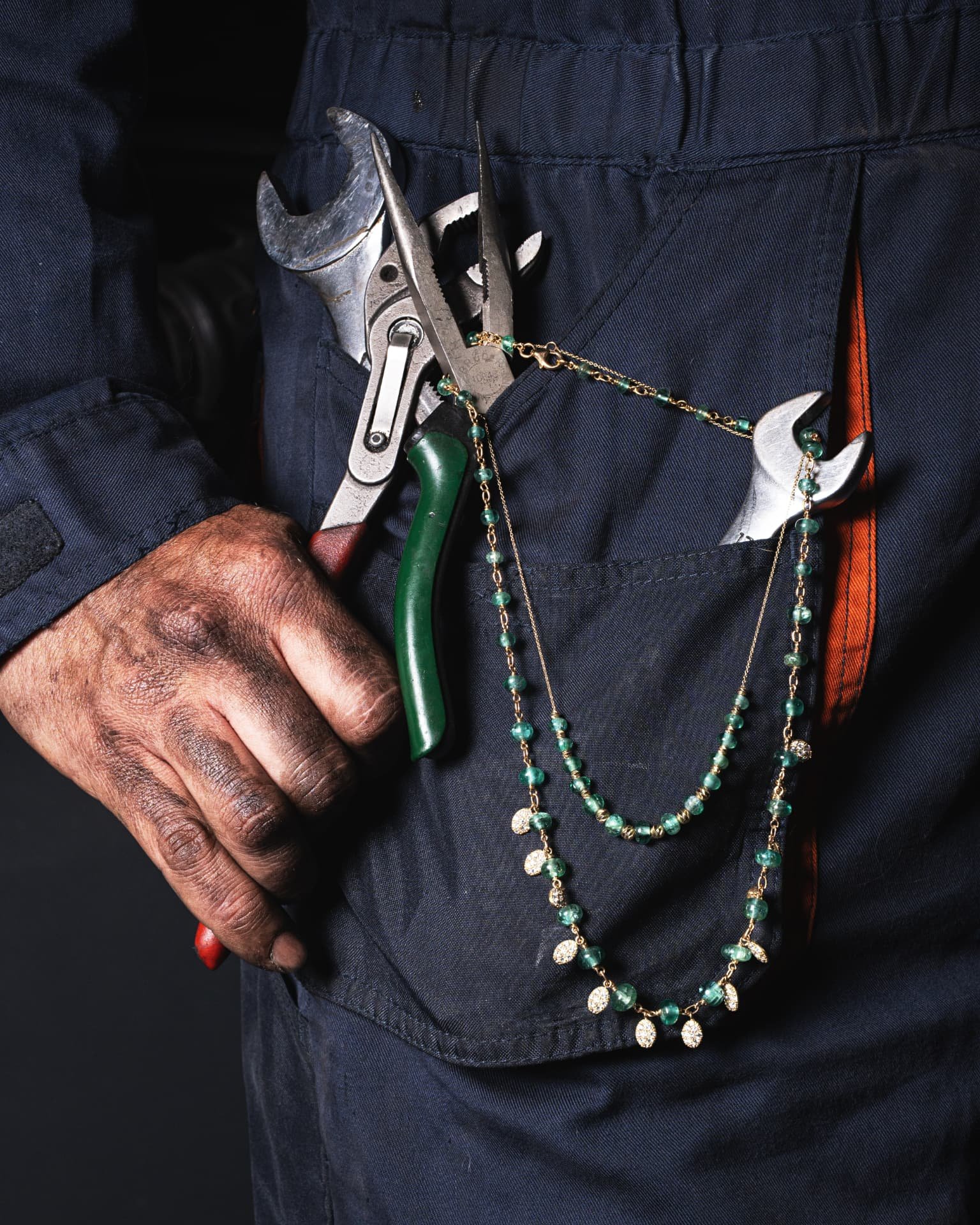 Collares de piedras verdes entre herramientas de taller