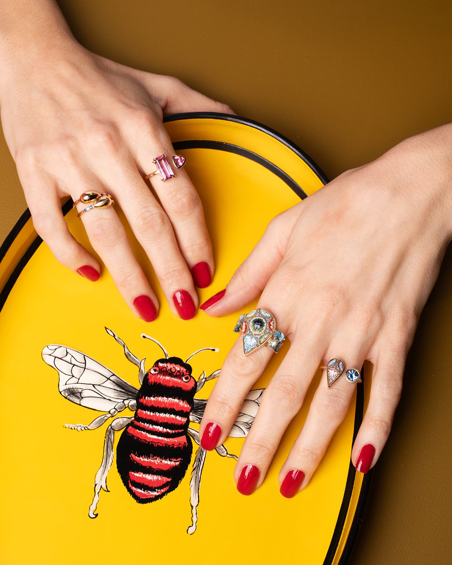 Manos con anillos sobre una bandeja amarilla ilustrada